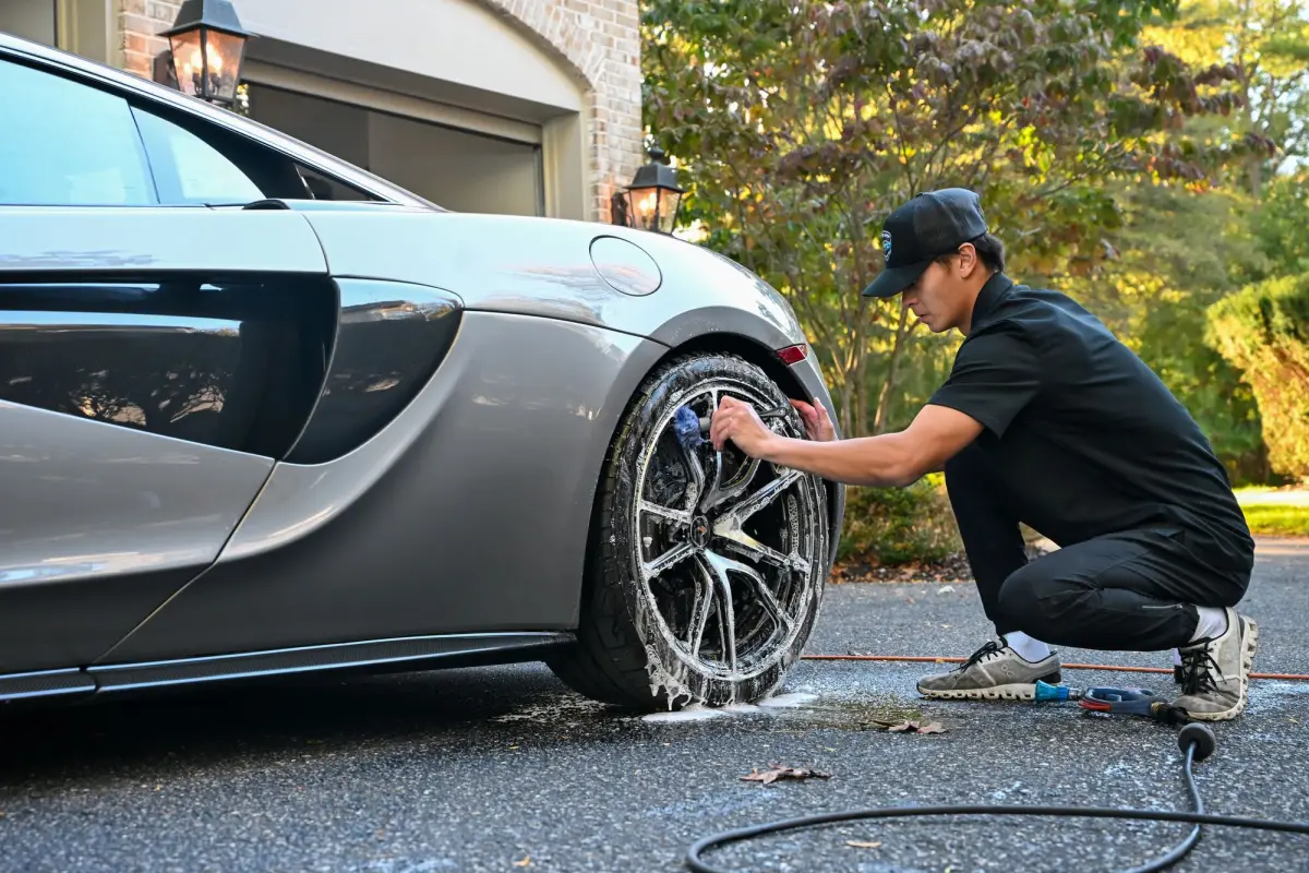 Nick cleaning a McLaren wheel in the driveway